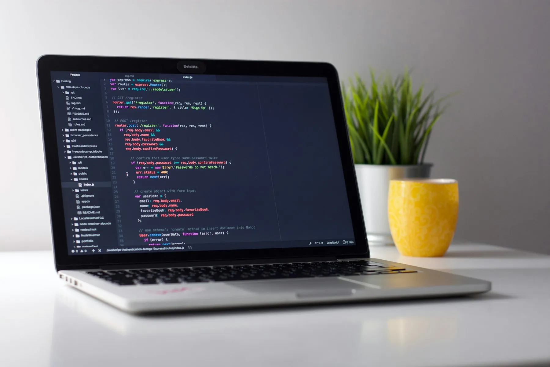 Laptop mit Quellcode auf einem aufgeräumten Schreibtisch